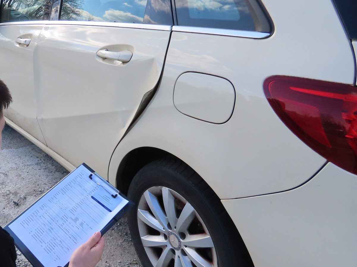 Kfz-Sachverständiger von Alterna nimmt eine eingedrückte Fahrzeugtür auf und notiert den Befund auf dem Aufnahmebogen